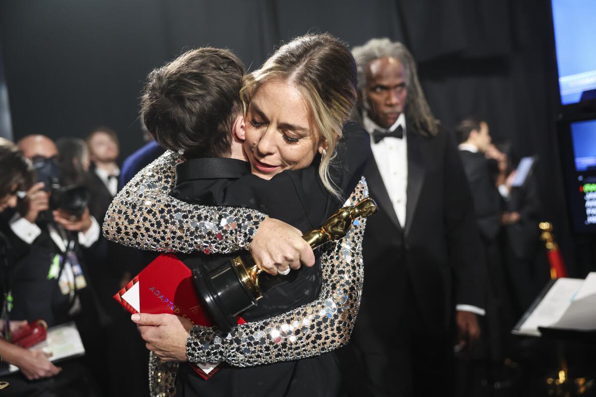 Sian Heder holds her statuette and hugs Elliott Page at the 2022 Oscars.