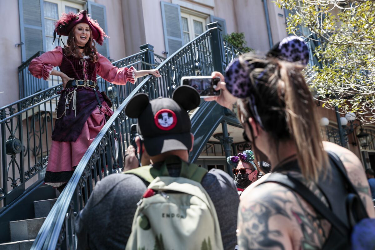 A woman in a pirate costume chatting with mouse-eared guests at Disneyland