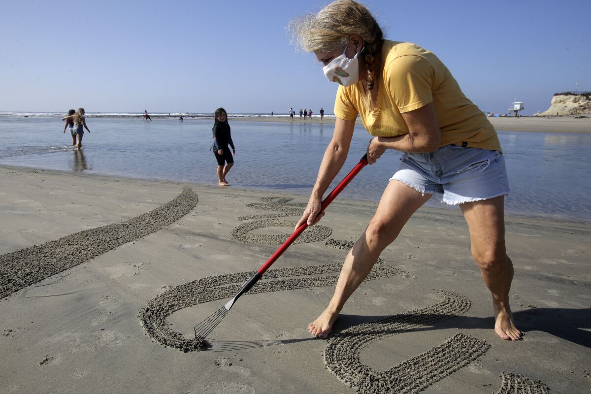Artist Sharon Belknap carves a mandala into the sand at Cardiff State Beach Wednesday. 