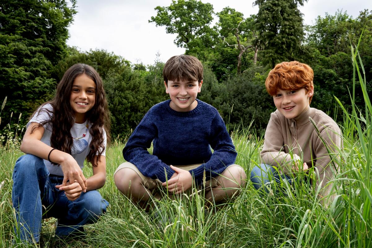 Arabella Stanton, Dominic McLaughlin and Alastair Stout crouch in the grass.