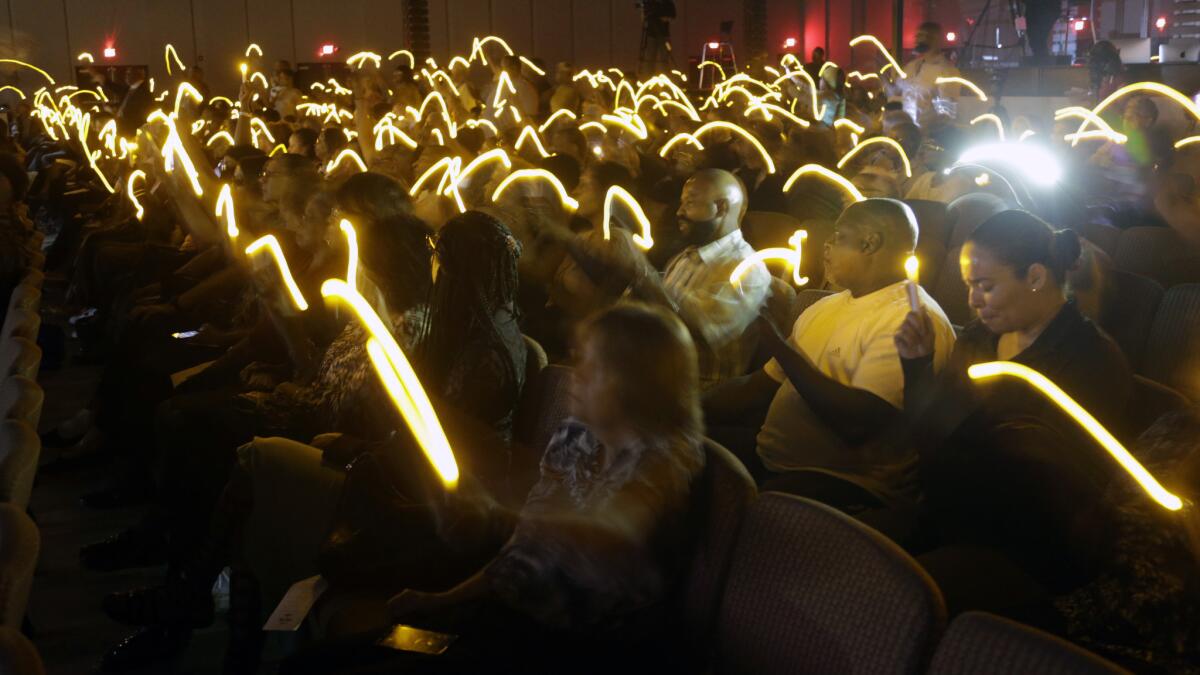 Mourners hold electric candles at a vigil Monday for Robert Hollis, who was found dead last week in his Inglewood apartment.