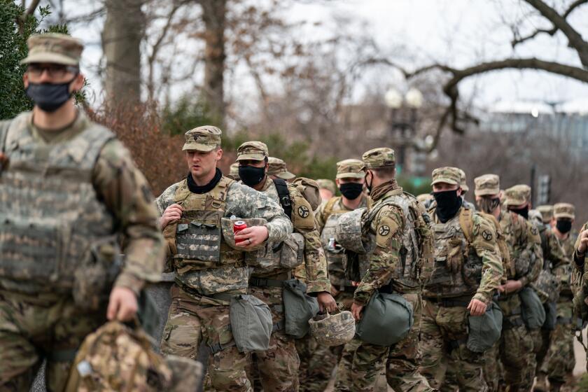 WASHINGTON, DC - JANUARY 18: National Guard troops disembark from a bus on Monday, Jan. 18, 2021 in Washington, DC. After last week's riots and security breach at the U.S. Capitol Building, the FBI has warned of additional threats in the nation's capital and across all 50 states. (Kent Nishimura / Los Angeles Times)