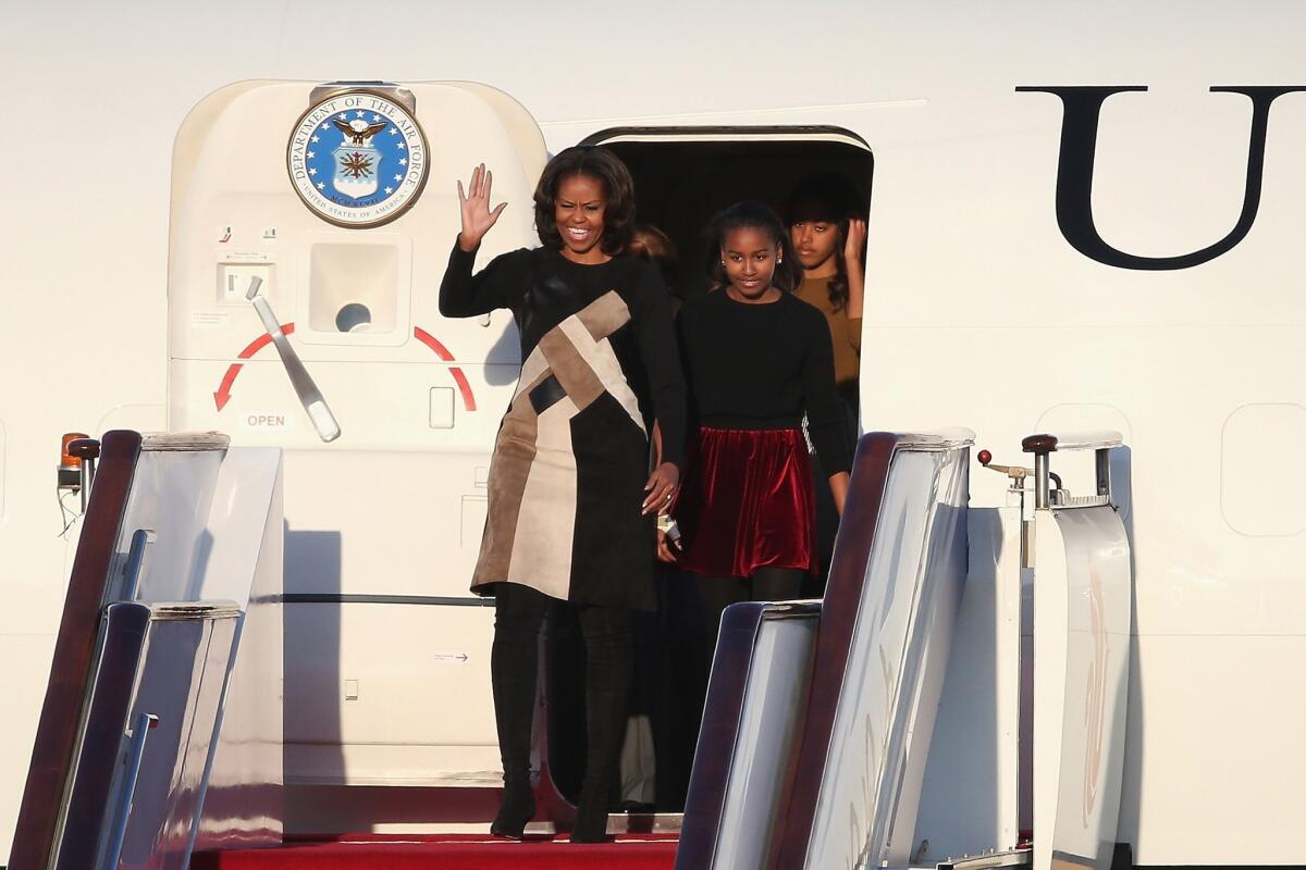 Michelle Obama, left, with her daughters Sasha and Malia, arrives at Beijing's airport.