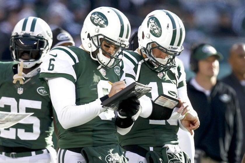 Former starting quarterback Mark Sanchez (6) and reserve Tim Tebow (15) check their playlist during the Jets' game against the Chargers on Sunday.