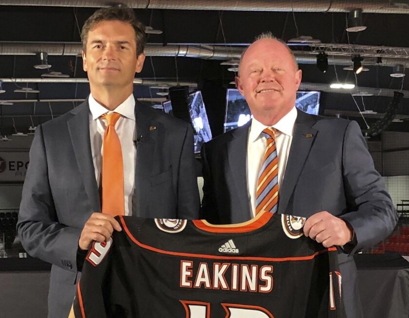 Ducks head coach Dallas Eakins, left, and general manager Bob Murray pose with a jersey at Great Park Ice in Irvine.