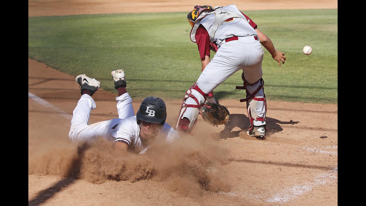 Laguna's Cutter Clawson dives across home plate safe as Estancia catcher tries to control the throw during boys' baseball on Wednesday.