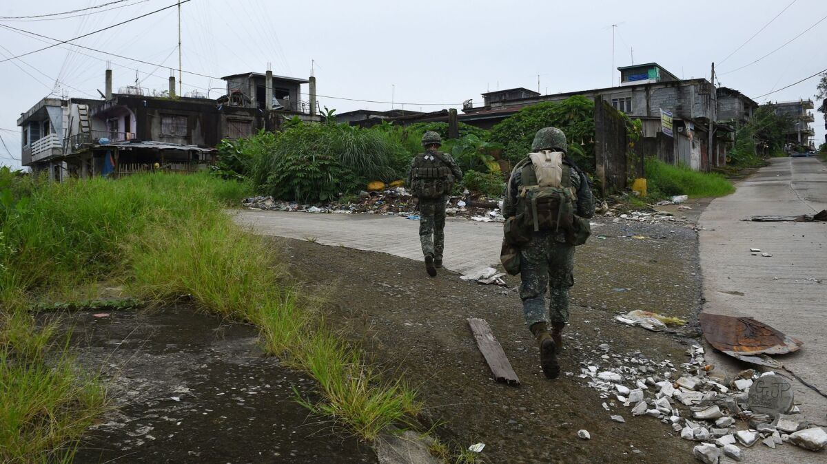 Philippine troops patrol a deserted neighborhood in Marawi on July 27, 2017.