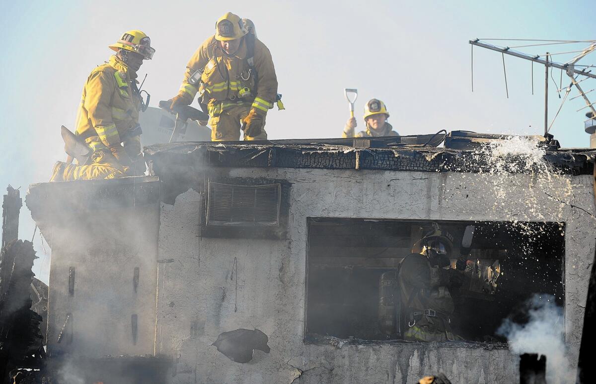 Firefighters battle a house fire in San Pedro in April. A string of lawsuits alleging bias in the department is costing the city millions of dollars.