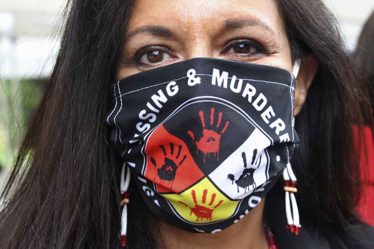 Woman poses in a Missing and Murdered Indigenous Women face mask