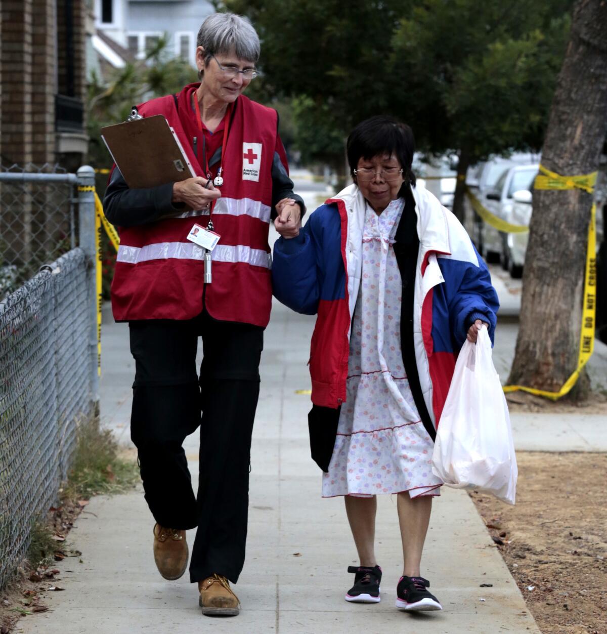 Pat Lynch with the American Red Cross Disaster Team Leader helps one of the displaced residents to gather her belongings from the Fairmont Apartments in Long Beach after a fire destroyed one of the units. Police officers rescued a man and woman from the burning apartment by prying security bars off with a wooden post.