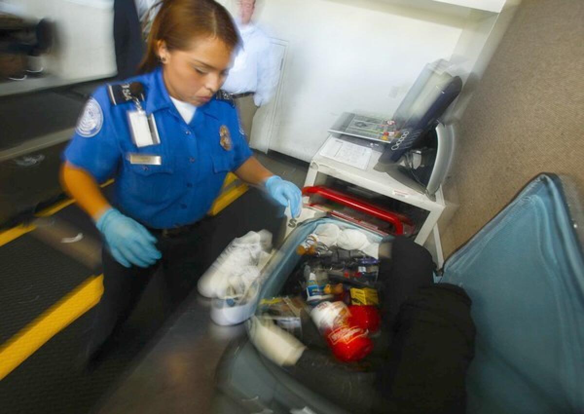 A TSA officer hand-inspects a traveler's bag at LAX.