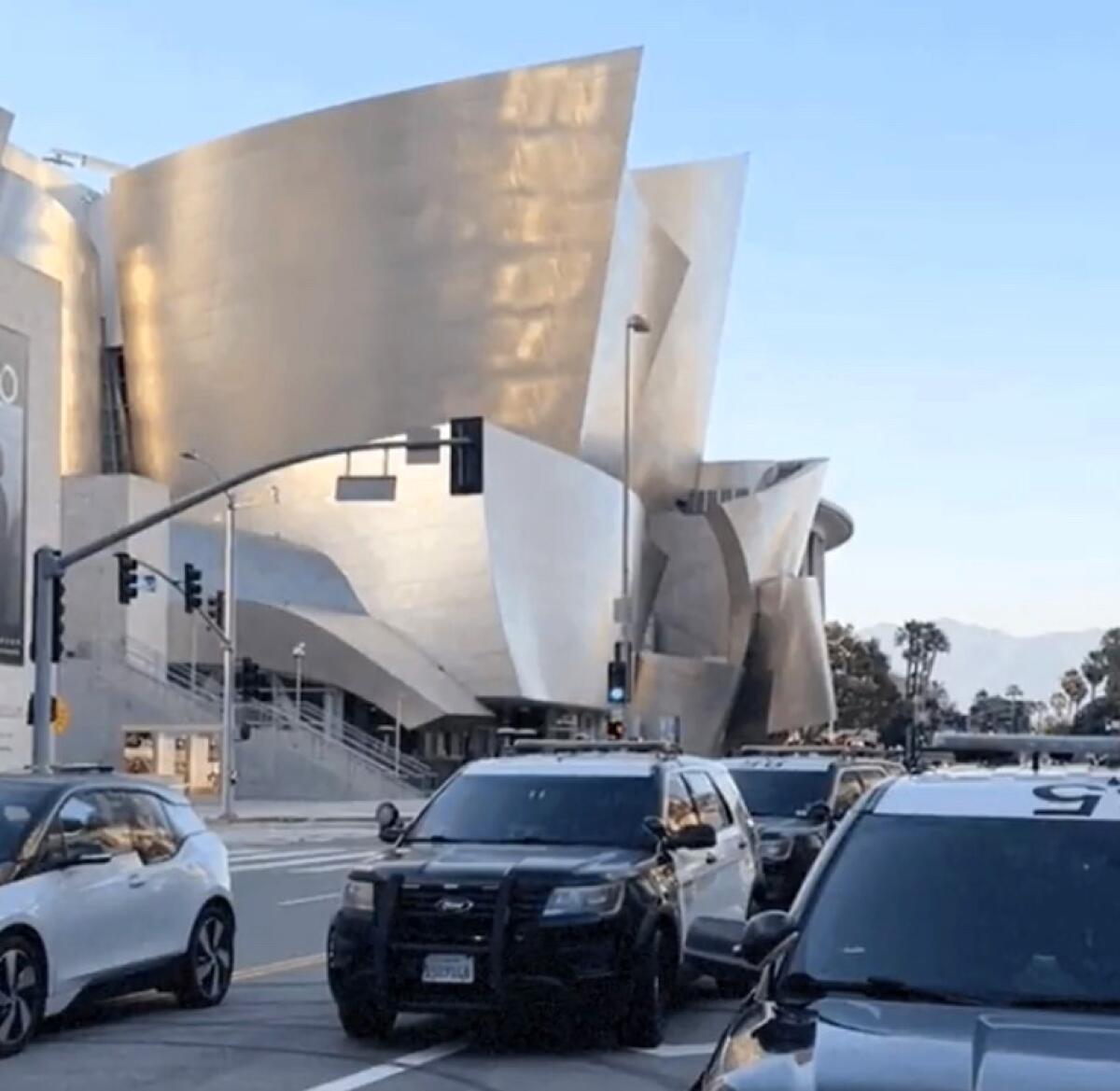 Police patrol vehicles are seen outside the Disney Concert Hall venue at dusk.