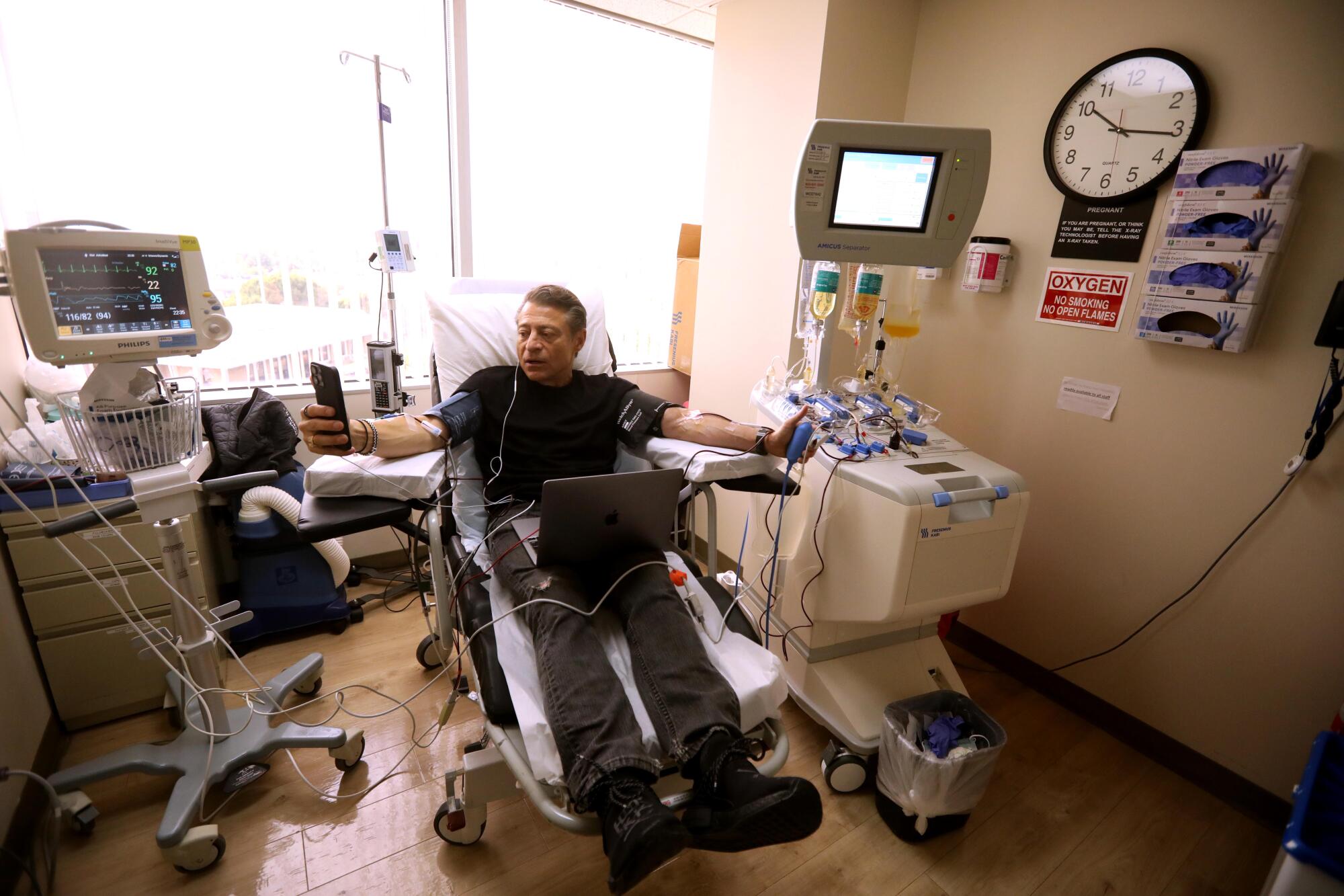 A man sits with medical machines and tubing at his sides.  