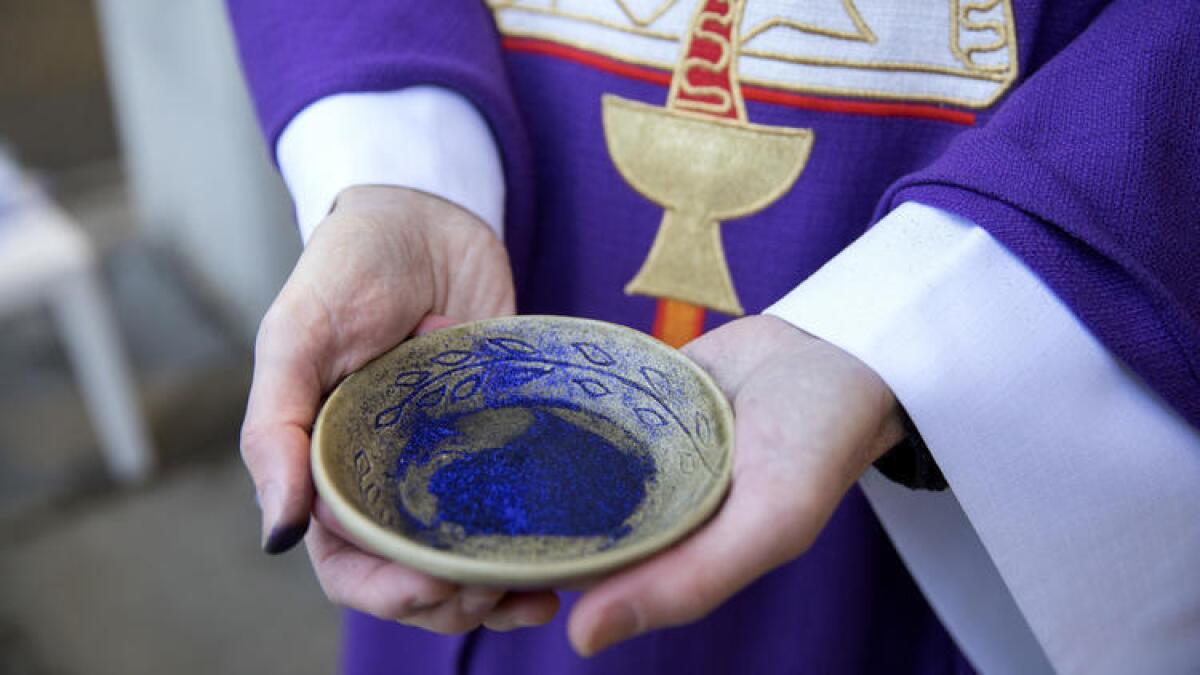 The Rev. Fred Kinsey of Unity Lutheran Church holds ashes mixed with glitter as he awaits commuters at a Red Line stop in Chicago.