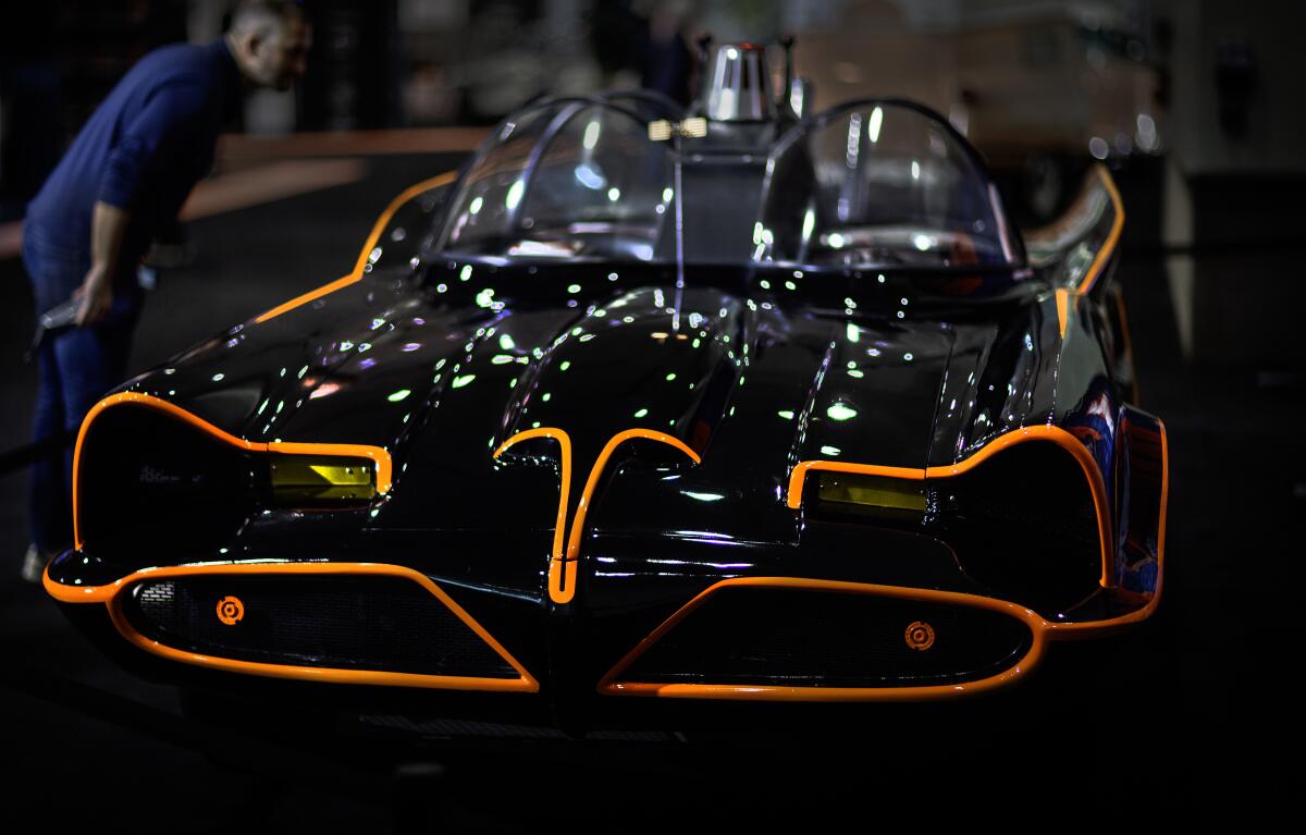 a man views a Batman-inspired black vehicle with orange detailing