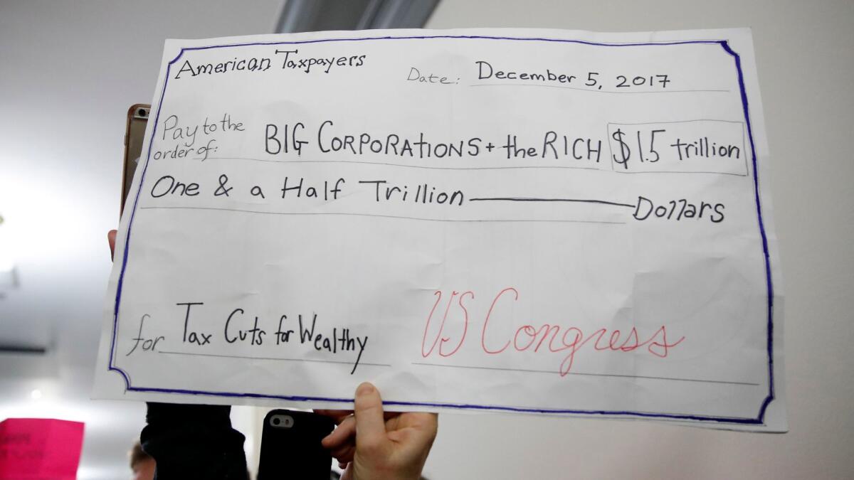 A man holds up a sign as people protest the Republican tax bill on Capitol Hill on Dec. 5.