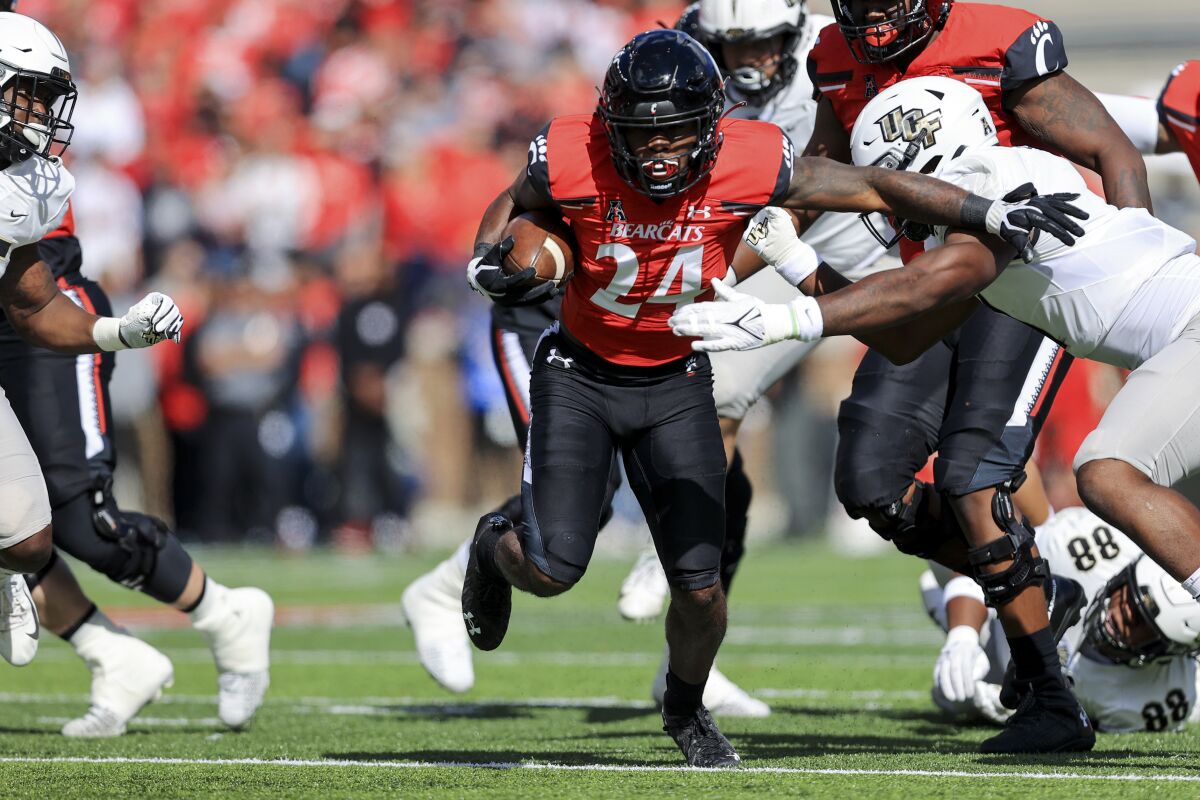 Cincinnati running back Jerome Ford (24) carries the ball as he breaks a tackle against UCF linebacker Jeremiah Jean-Baptiste, right, during the first half of an NCAA college football game, Saturday, Oct. 16, 2021, in Cincinnati. (AP Photo/Aaron Doster)
