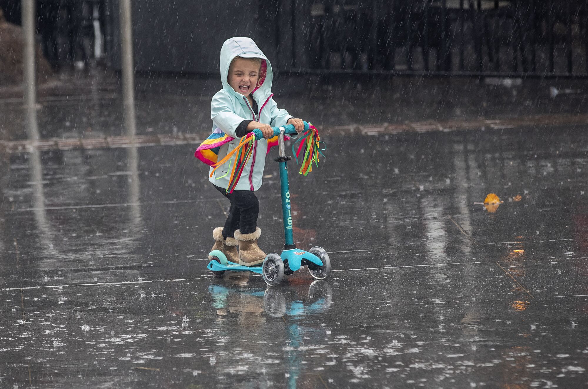 A young girl rides her scooter in the rain