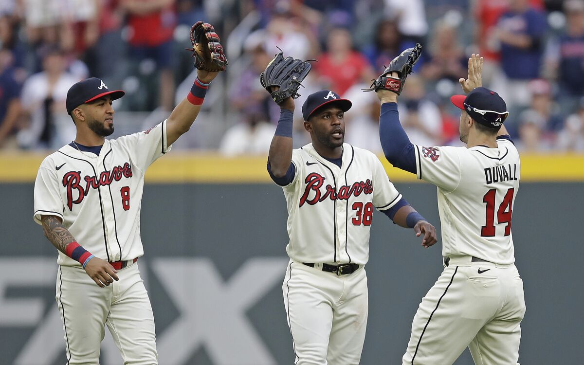 Atlanta Braves outfielders, from left to right, Eddie Rosario (8), Guillermo Heredia and Adam Duvall (14) celebrate at the end of a baseball game against the New York Mets, Sunday, Oct. 3, 2021, in Atlanta. (AP Photo/Ben Margot)