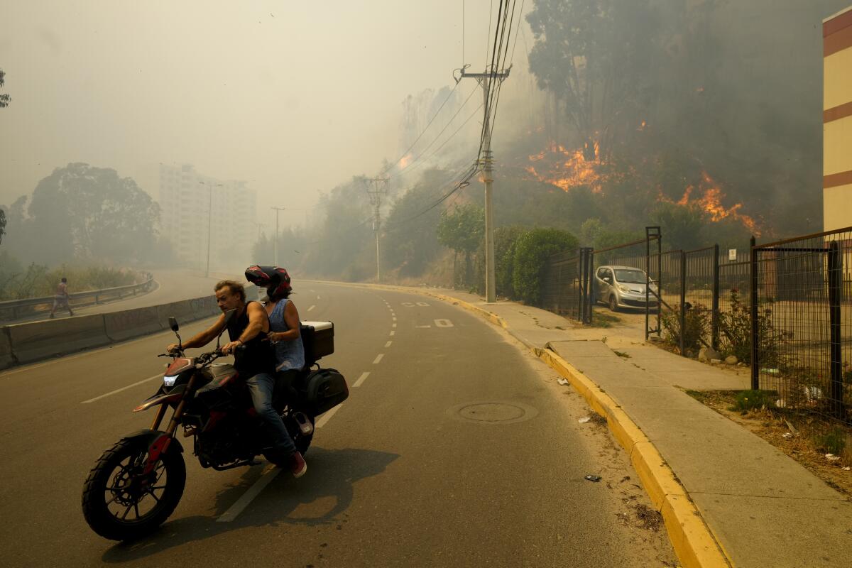 Residents evacuate on a motorcycle amid wildfires in Chile.
