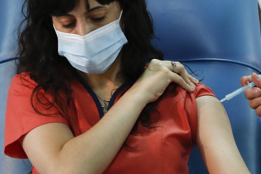 Dr. Estefania Zevrnja gets a shot of Russia's Sputnik V vaccine for COVID-19 at Dr. Pedro Fiorito Hospital in Avellaneda, Argentina, Tuesday, Dec. 29, 2020. (AP Photo/Natacha Pisarenko)