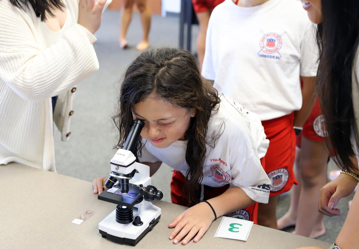Ella Truong, 9, looks through a microscope to see closely healthy skin during Monday's STEM education session.