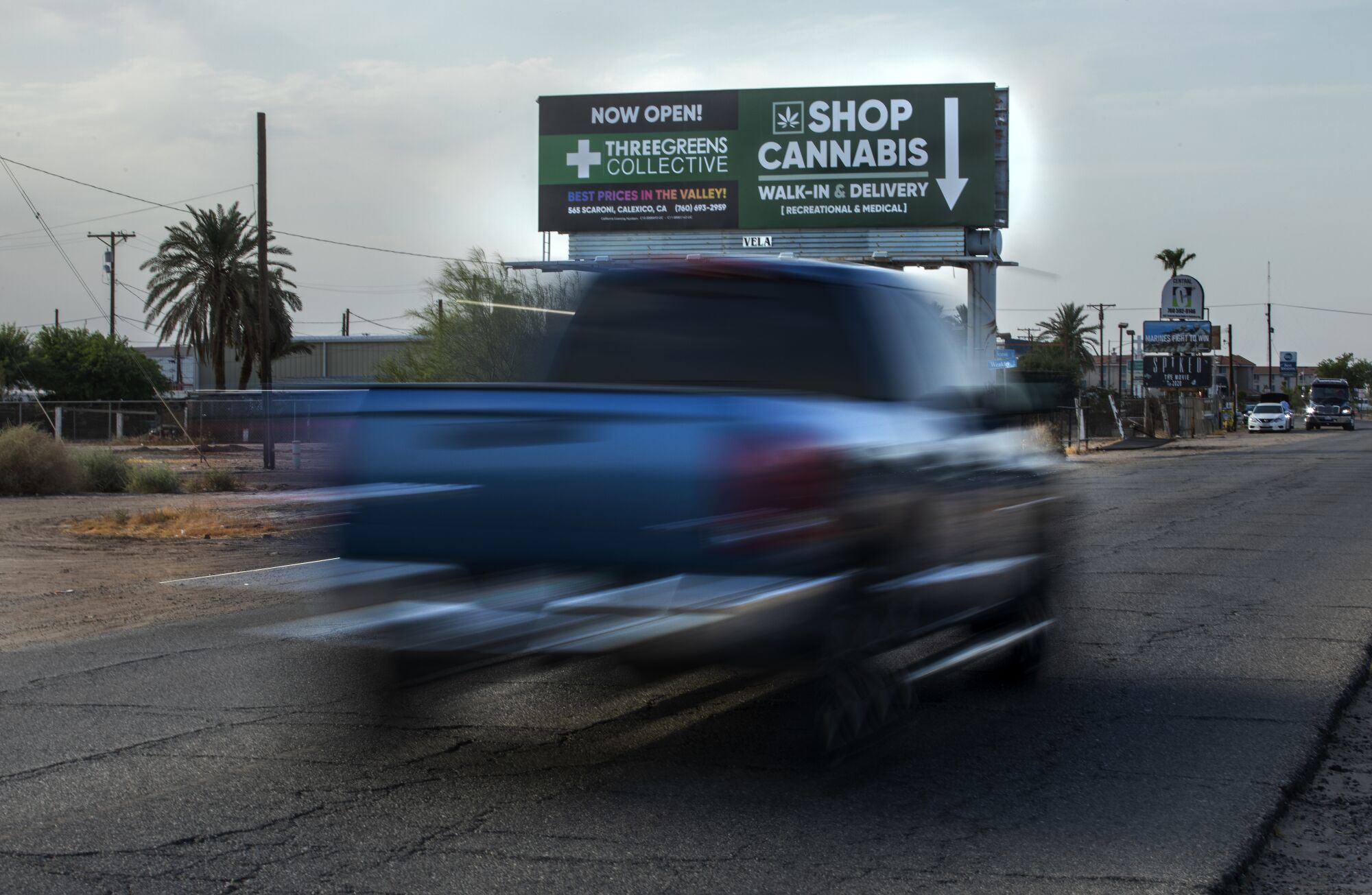 A truck drives by a billboard advertising a cannabis business.