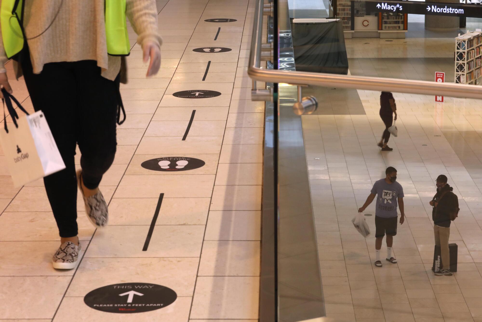 Floor signs with arrows and footprints are spaced several feet apart to encourage social distancing.