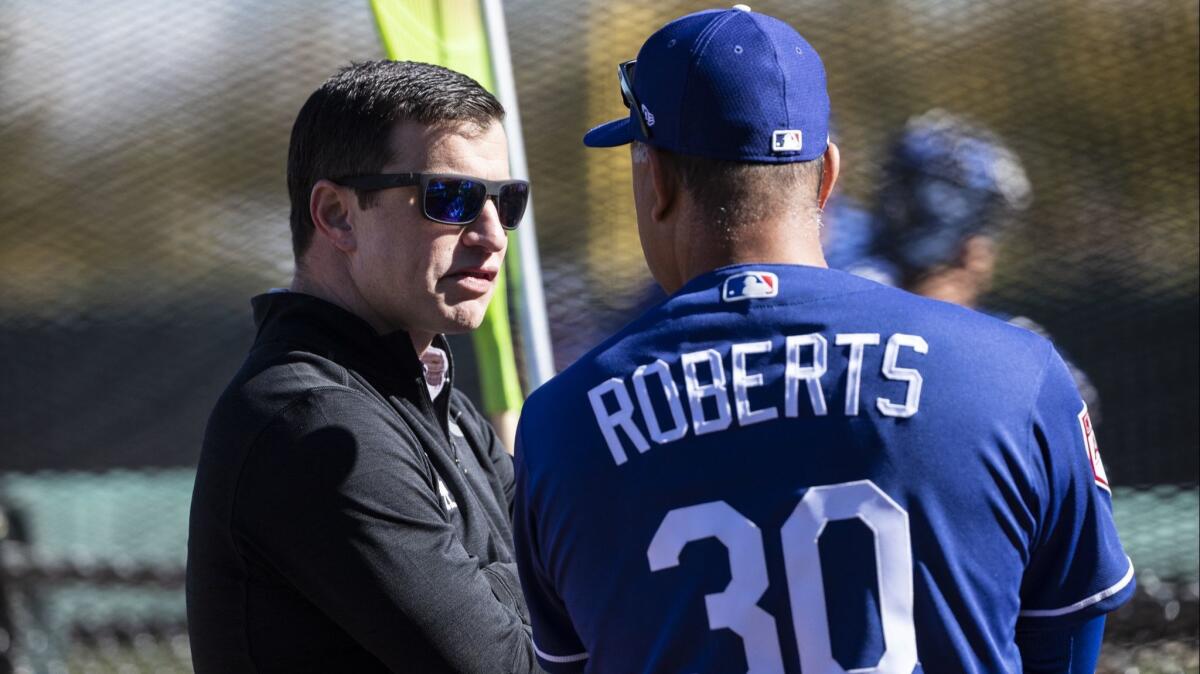 Andrew Friedman, the Dodgers’ president of baseball operations, speaks with manager Dave Roberts during spring training at Camelback Ranch in February.