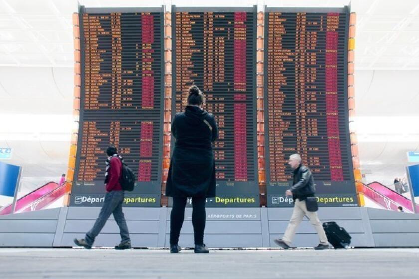 Travelers pass by a board announcing flights canceled as the result of a cloud of volcanic ash from Iceland at the Roissy Charles de Gaulle Airport near Paris in 2010.