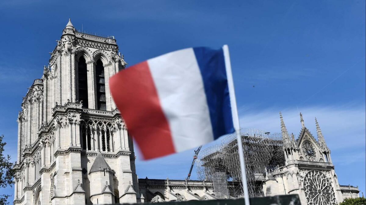 A French flag attached to a kiosk flutters close to Notre Dame cathedral on Wednesday, two days after a fire engulfed the 850-year-old gothic masterpiece, destroying the roof and causing the steeple to collapse.