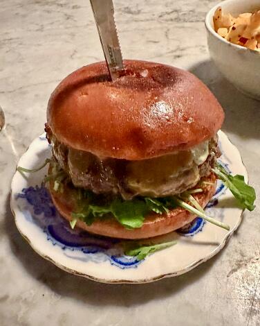 A burger sitting on a ceramic plate.