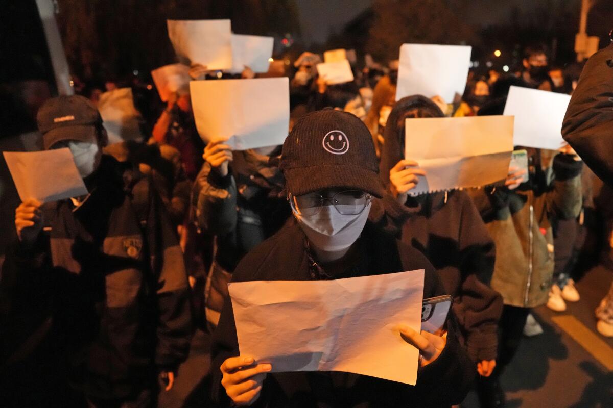 Protesters hold up blank papers and chant slogans as they march in protest in Beijing.