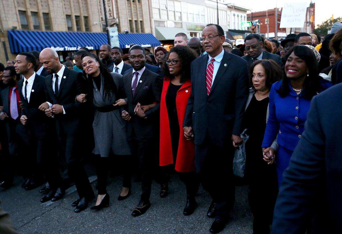 Oprah Winfrey, in red, leads a Martin Luther King Jr. Day march in Selma, Ala., with cast and crew of the film "Selma." They include, to the left of Winfrey, actor David Oyelowo, director Ava DuVernay, actor and songwriter Common and singer and songwriter John Legend.