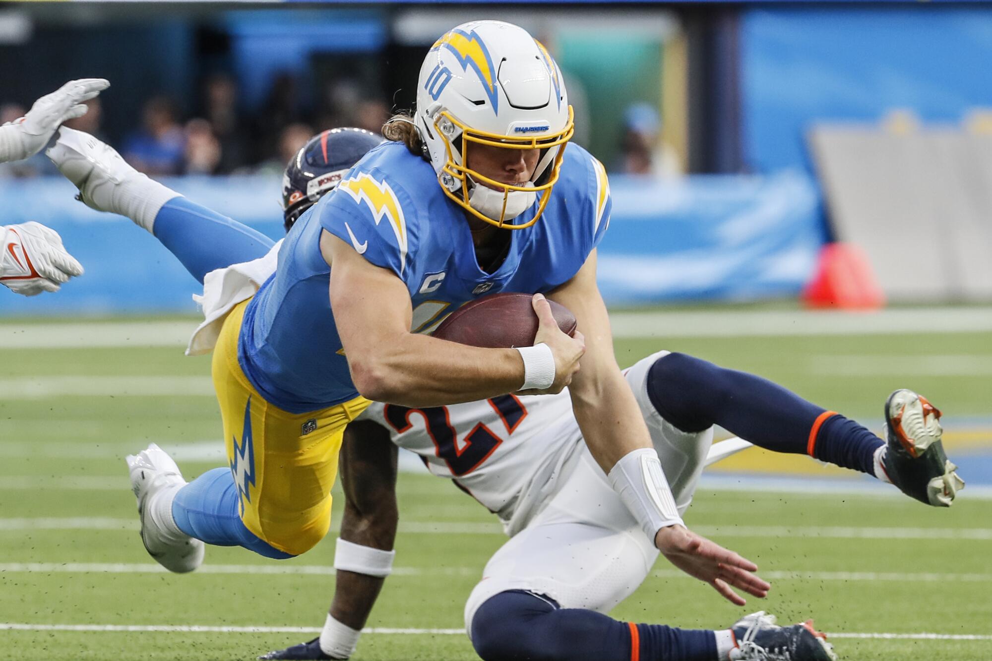 Chargers quarterback Justin Herbert dives for a first down in front of Denver Broncos cornerback Ronald Darby.