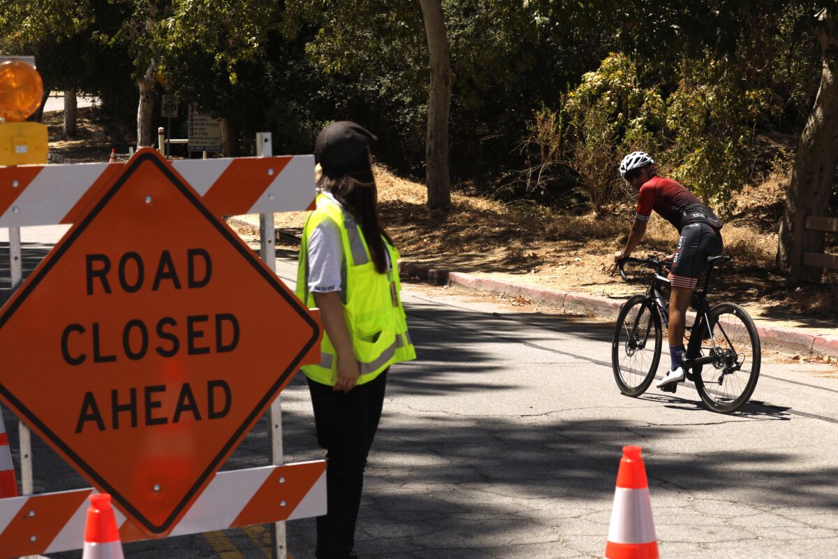 A cyclist passes a "road closed ahead" sign. 
