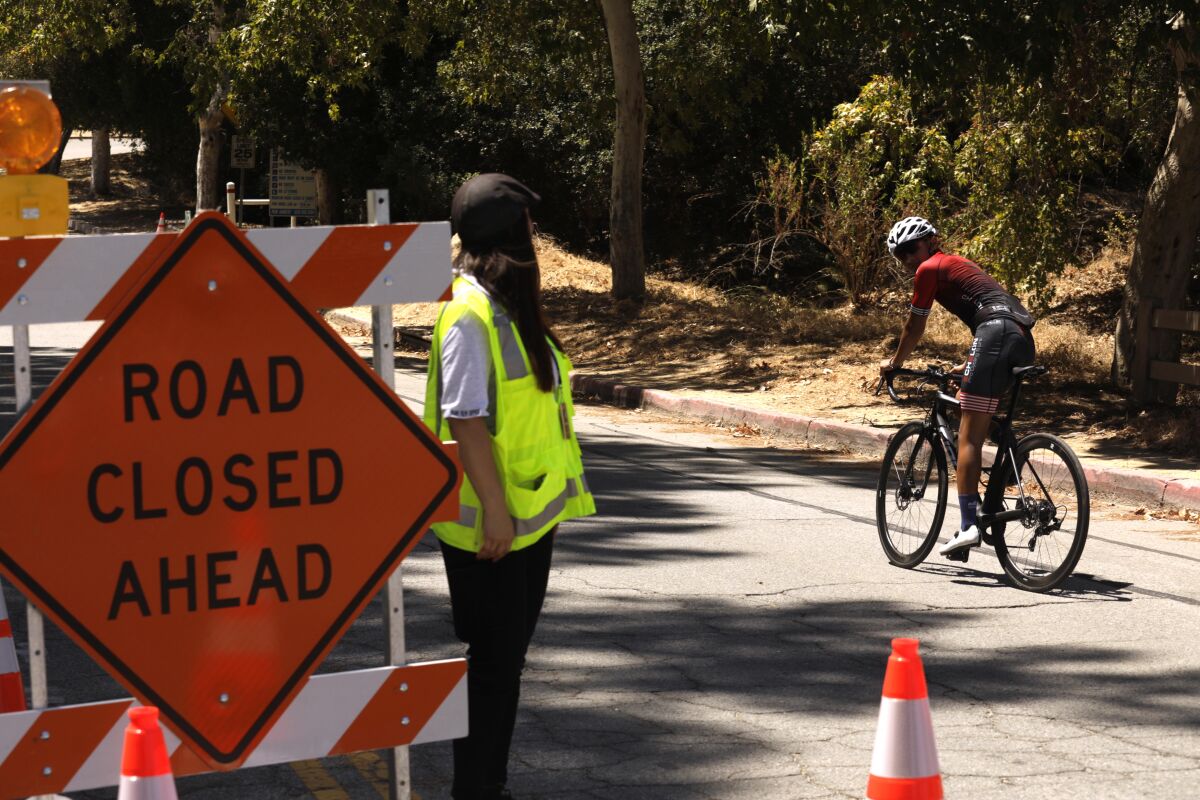 A cyclist passes a "road closed ahead" sign.