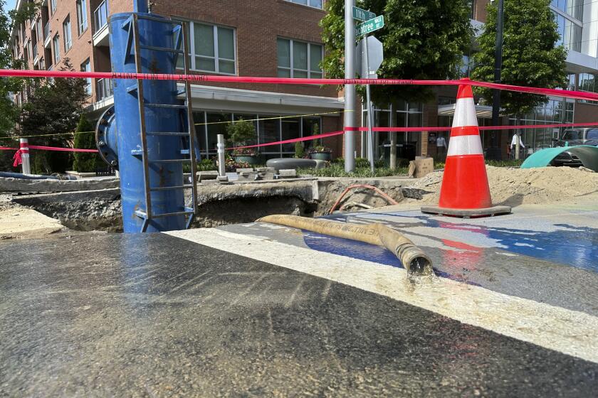 Water trickles out of a hose attached to a device that shuts off flow to a water main on Monday, June 3, 2024, in Atlanta. The device was one of several used to shut off flow to a leak that had gushed for more than two days in Atlanta's Midtown neighborhood. (AP Photo/Jeff Amy)