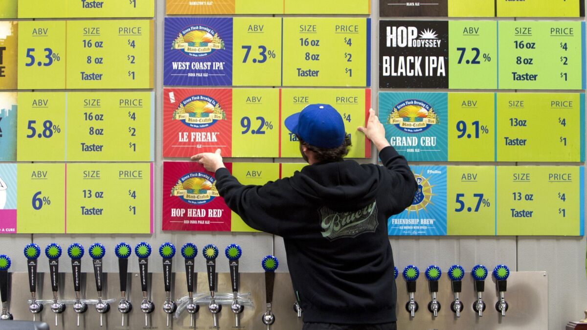 In a 2014 photo, John Silveria adjusts the beer menu at Green Flash's Mira Mesa tasting room.