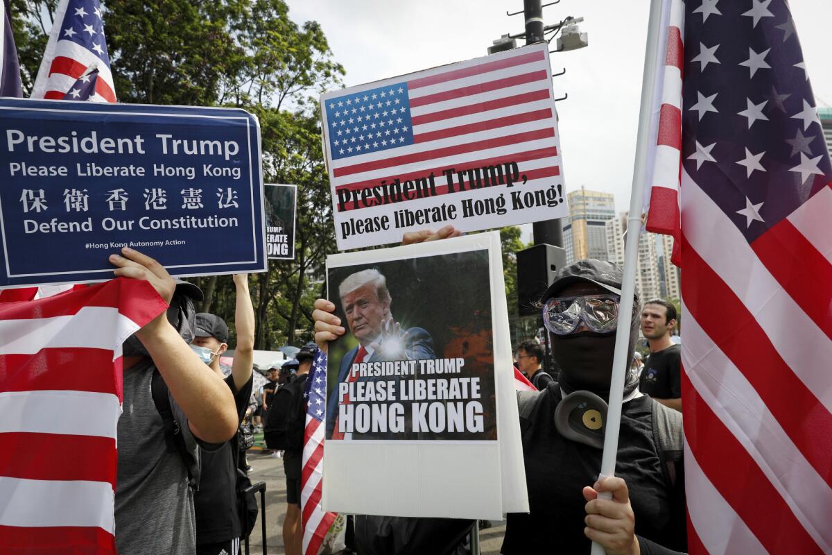 Manifestantes mostrando una pancarta con banderas estadounidenses y la imagen del presidente de Estados Unidos y la frase "Presidente Trump, por favor, libere Hong Kong, durante una marcha en el Parque Victoria de Hong Kong, el domingo 21 de julio de 2019. (AP Foto/Vincent Yu)