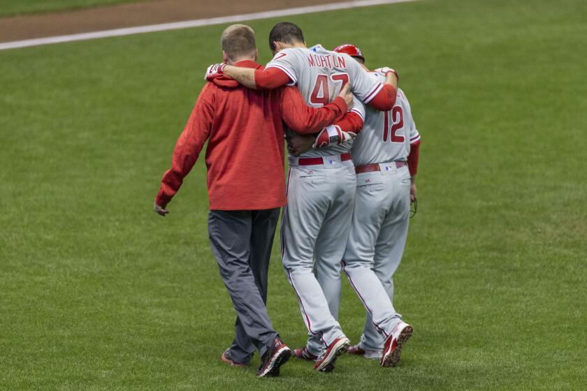 Phillies starting pitcher Charlie Morton, center, is helped off the field after injuring his hamstring during the second inning against the Brewers.