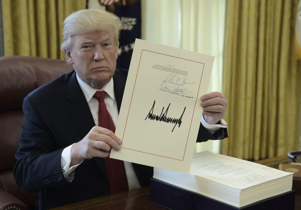 President Trump holds up a document during an event to sign the Tax Cut and Reform Bill at the White House in 2017.