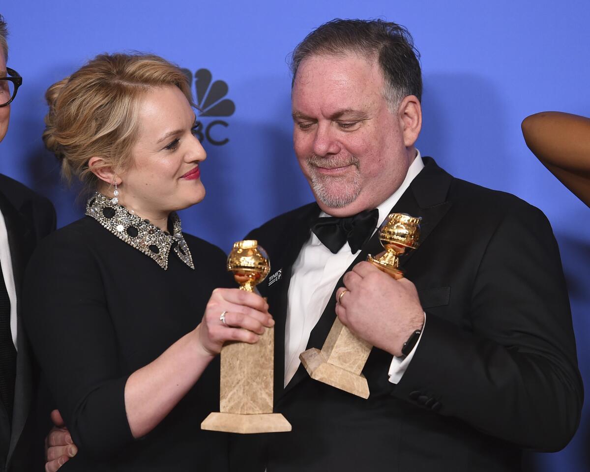 "Handmaid's Tale" star Elisabeth Moss and series creator Bruce Miller pose with their awards backstage at the Golden Globes on Sunday.