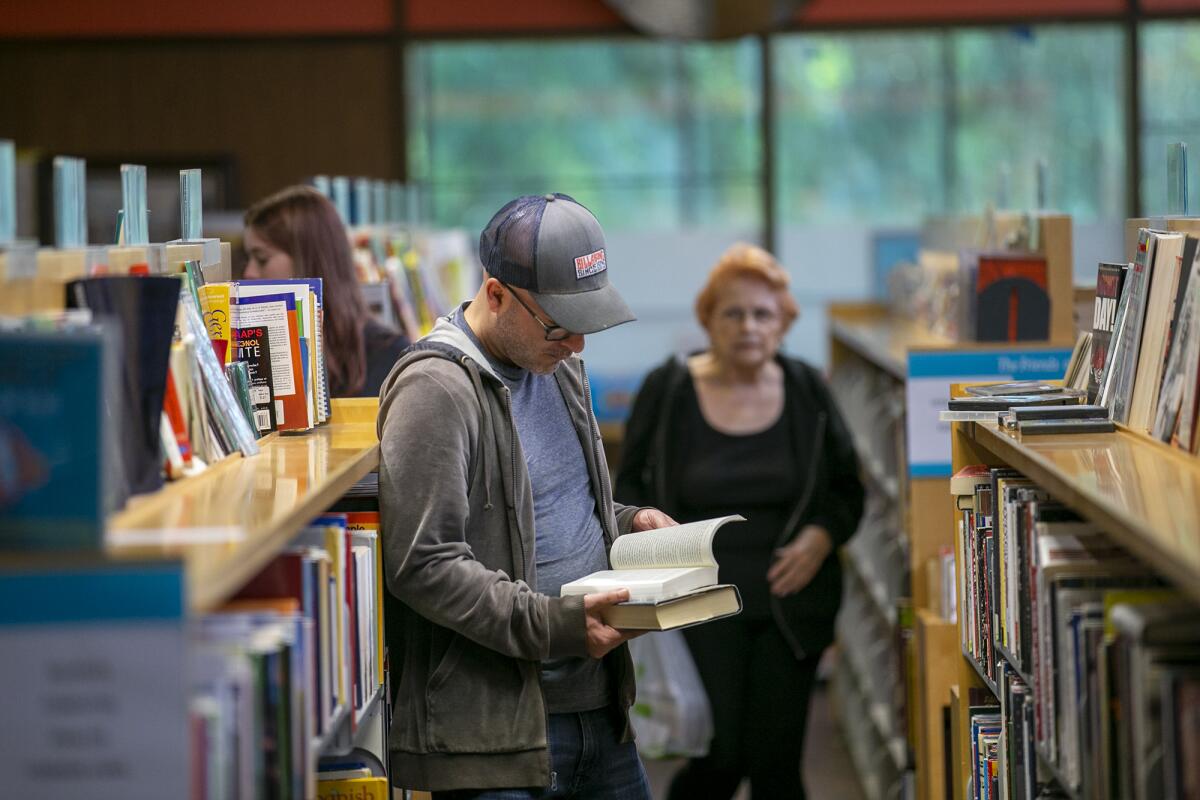 Stephen Echeverria looks at a book in the used book section of the Huntington Beach Central Library on Monday.