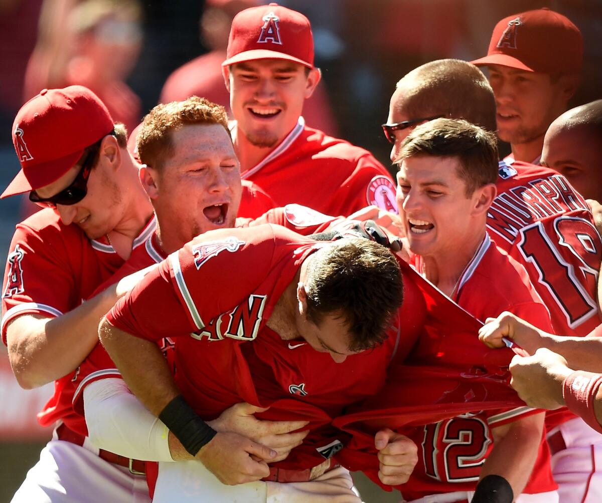Angels third baseman Taylor Featherston is mobbed by teammates including Johnny Giavotella (12) after scoring the winning run on a wild pitch in the ninth inning.