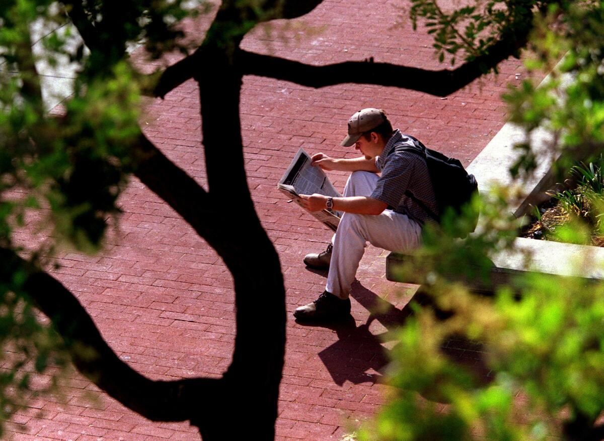 A UC Irvine student reads a copy of the campus newspaper New University between classes.