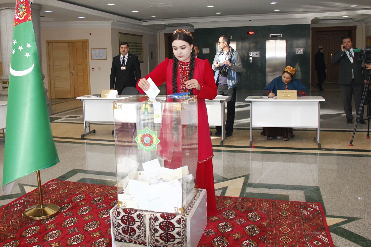 A woman wearing a national costume casts her ballot at a polling station in Ashgabat, Turkmenistan, Sunday, March 26, 2023. Voters in Turkmenistan have cast ballots for a new parliament that is expected to be opposition-free and loyal to the government of the gas-rich Central Asian nation. Sunday's election for 125 members included 258 candidates, put forward by three political parties or running independently. (AP Photo/Alexander Vershinin)