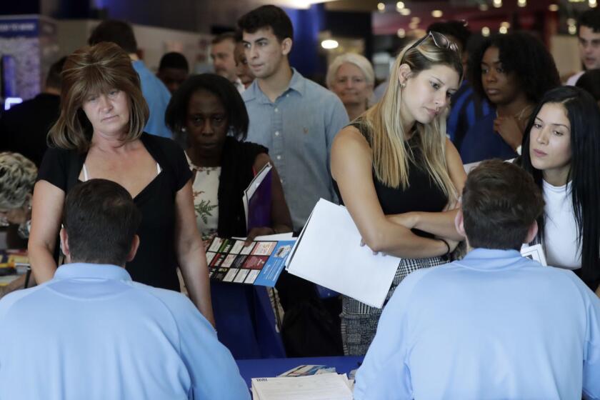 FILE- In this June 21, 2018, file photo, job applicants talks with representatives from Aldi at a job fair hosted by Job News South Florida, in Sunrise, Fla. On Friday, Oct. 5, the U.S. government issues the September jobs report. (AP Photo/Lynne Sladky, File)