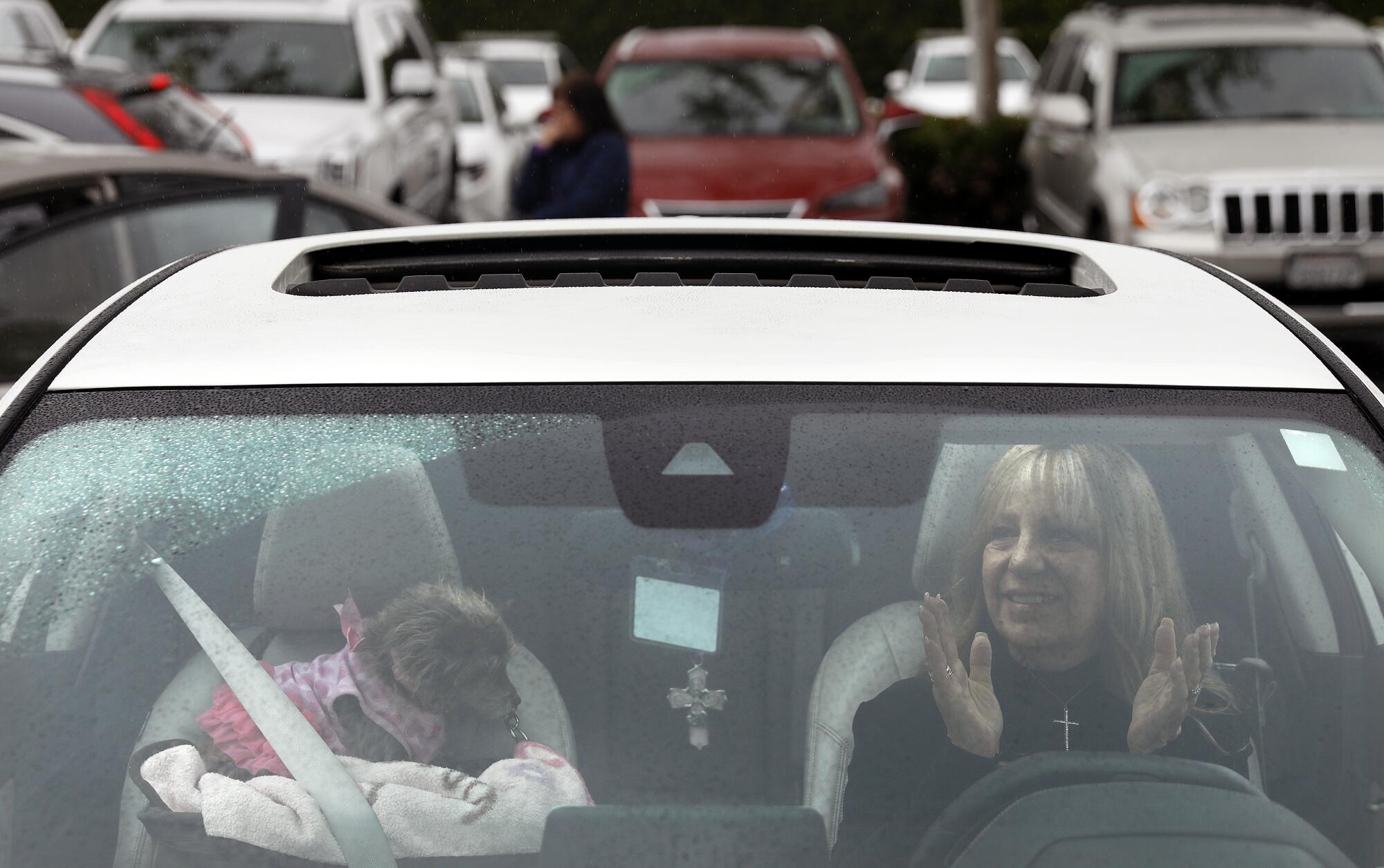 Kurner of Corona with her 9-year-old dog Stella Mae along with other worshippers gather in their cars in a parking lot in Santa Ana to worship in an Easter service by Rev. Robert A. Schuller on Sunday. "People need a place to go to worship on Easter, " he said.