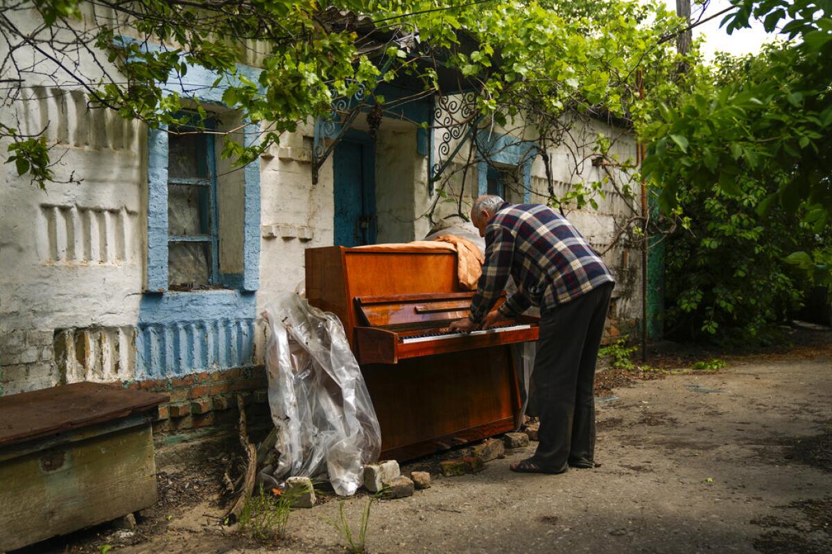 Anatolii Virko toca un piano fuera de una casa 
